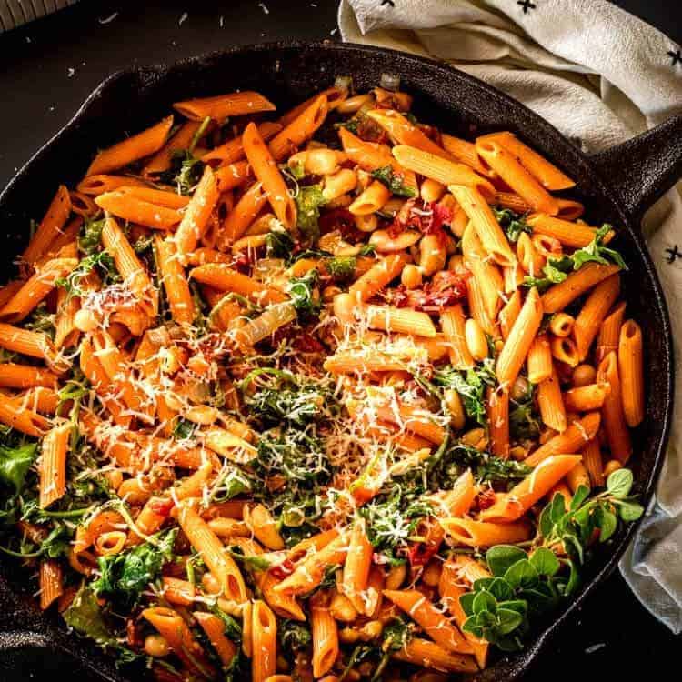 Instant Pot Cannelini Beans with Penne, Arugula, and Slow Roasted Tomatoes - square feature image in cast iron skillet.