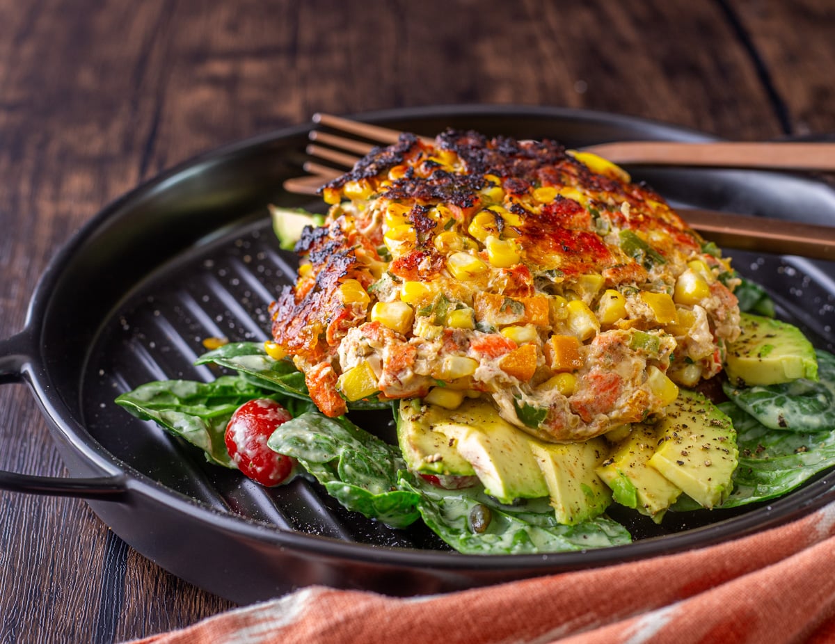 Spicy Mexican Salmon Patties with Creamy Cilantro Ranch and Spinach Salad - a white square plate with a completed Mexican salmon patty atop spinach salad with cilantro ranch dressing.