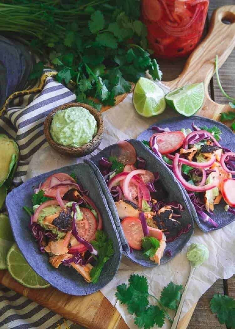 Blackened Salmon Tacos in blue corn tortillas on a cutting board.