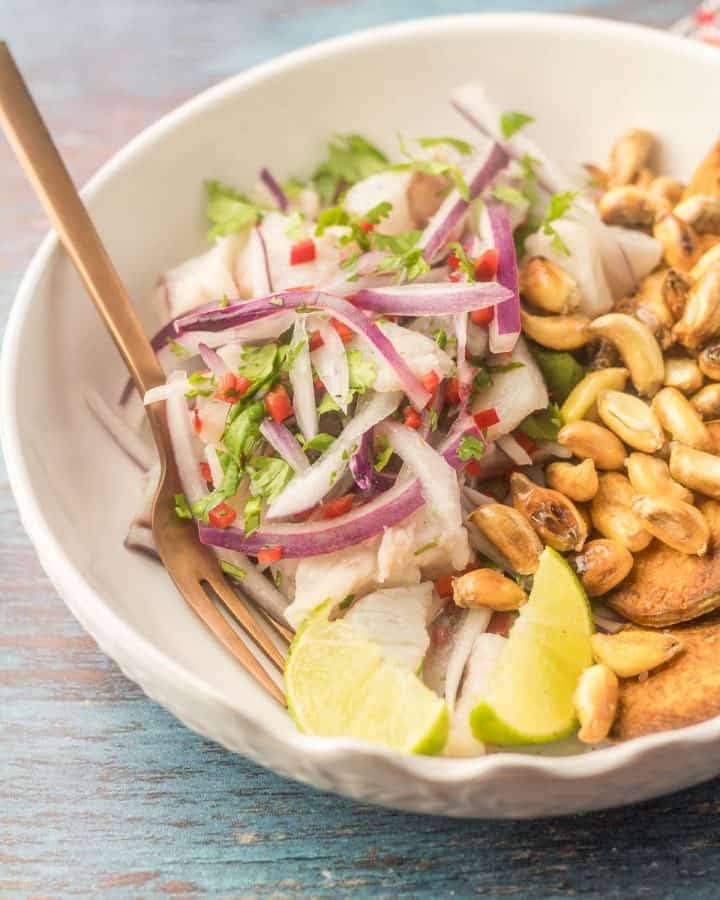 A white ceramic bowl with Peruvian ceviche and a copper fork.