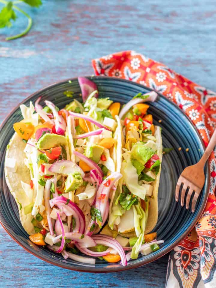A blue ceramic plate with 3 Peruvian style fish tacos.