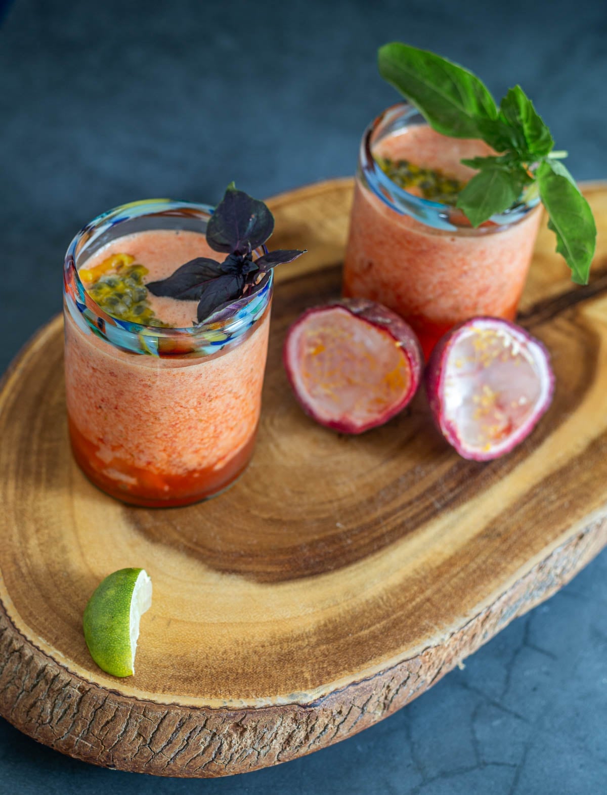 2 tall highball glasses with Strawberry Passionfruit Agua Fresca with Passionfruit, and garnished with lime, mint, and passionfruit seeds.
