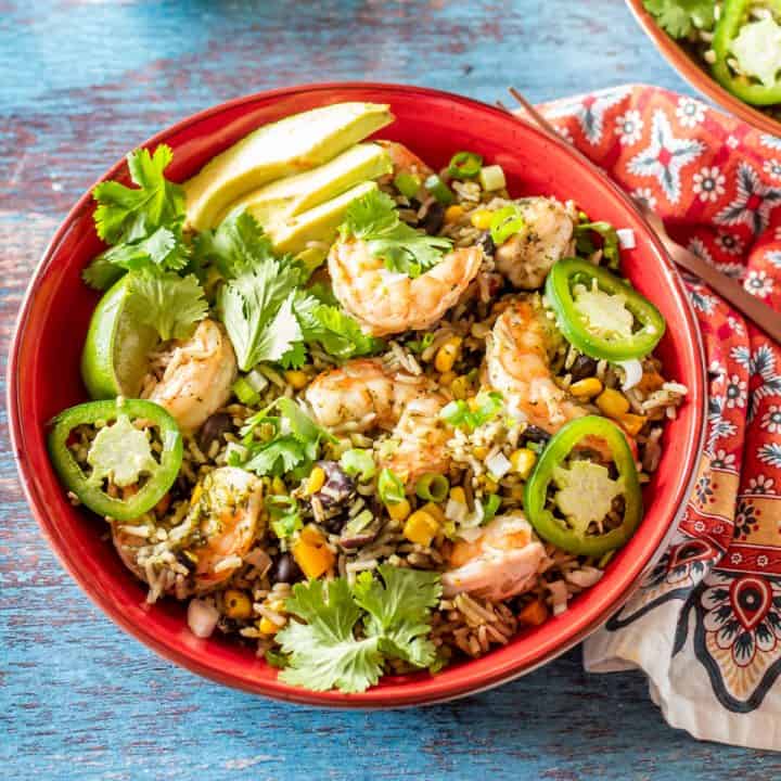 Mexican Arroz con Camarones (Rice and Shrimp) in a black bowl with a black fork and a red print napkin.