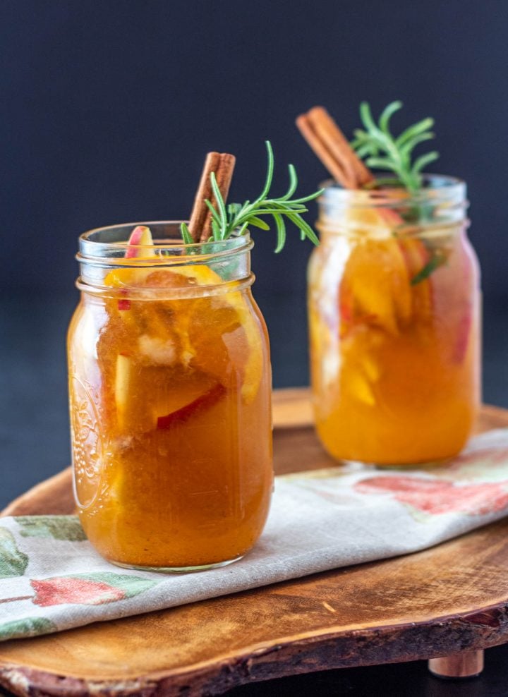 2 glass mugs of fall pumpkin sangria on a live edge wood tray.