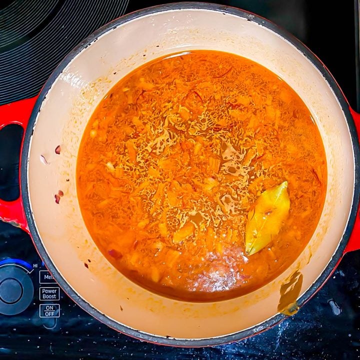 The saffron and seafood broth is added into the pot with the chorizo.
