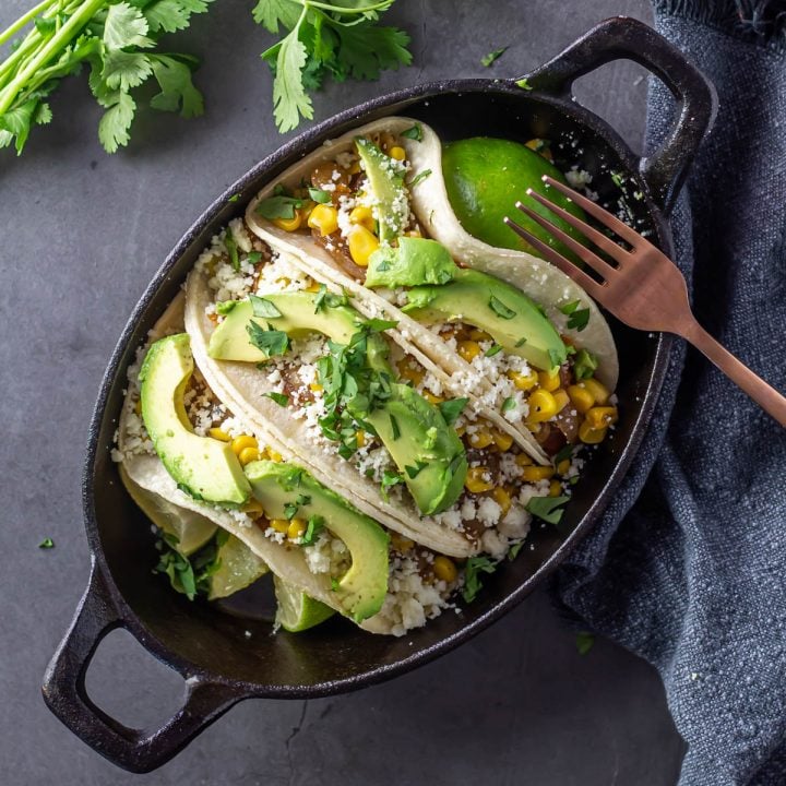 A cast iron casserole with 3 Nopales Tacos and toppings.