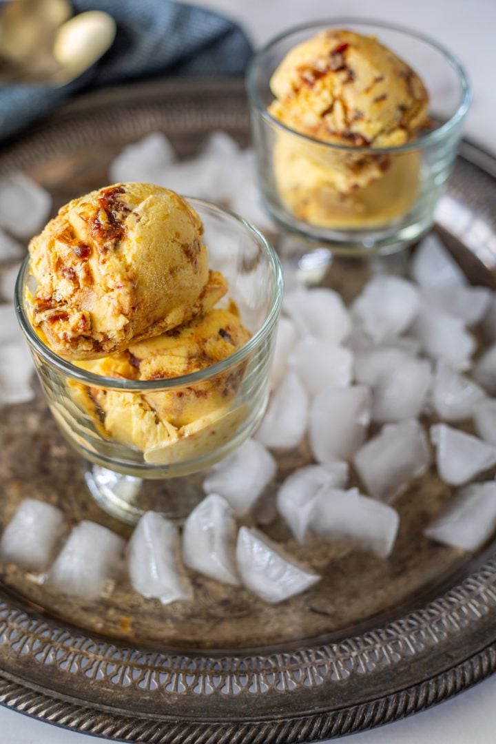 Mango and chamoy ice cream in glass dishes on a tray with ice.