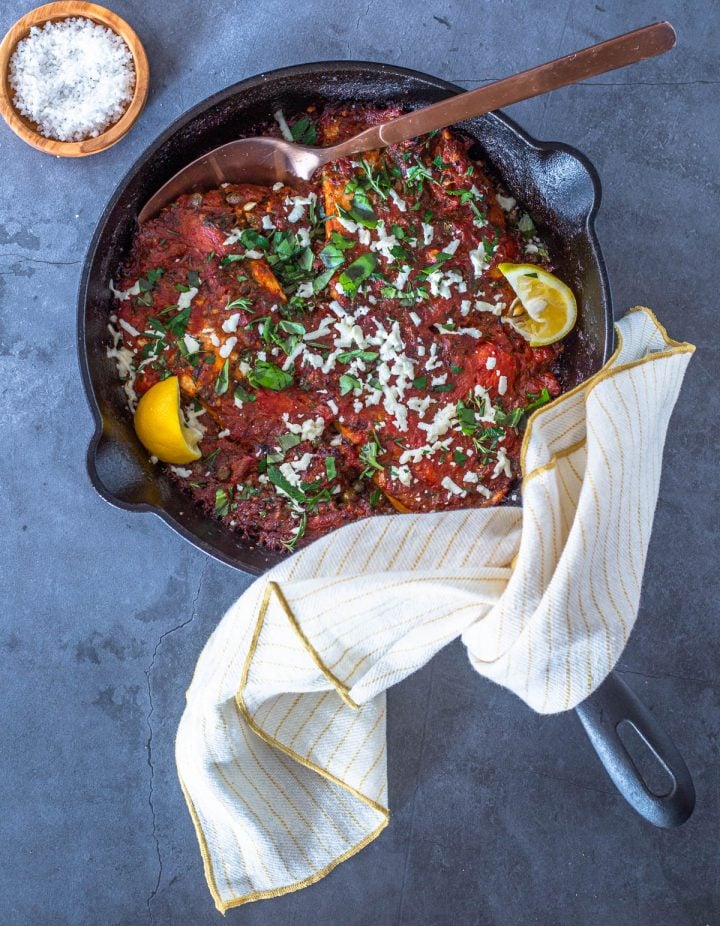 Baked Mediterranean Fish Fillets with Lemony Orzo on a round black ceramic plate with black flatware. It's low calorie, Mediterranean diet compliant, clean, delicious!