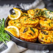 Healthy Mediterranean cottage cheese egg bites on a black ceramic tray with herbs and lemon.