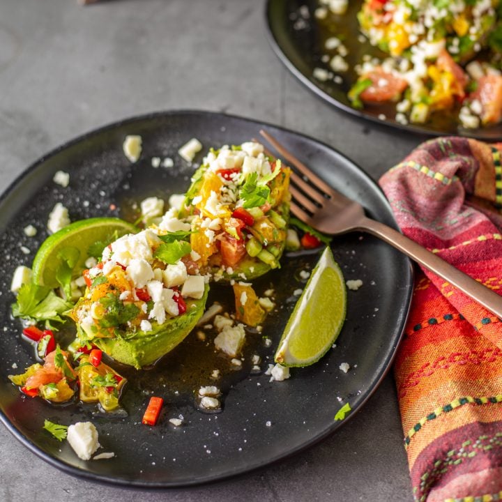 Mexican avocado salad with Citrus Vinaigrette on a black ceramic plate.