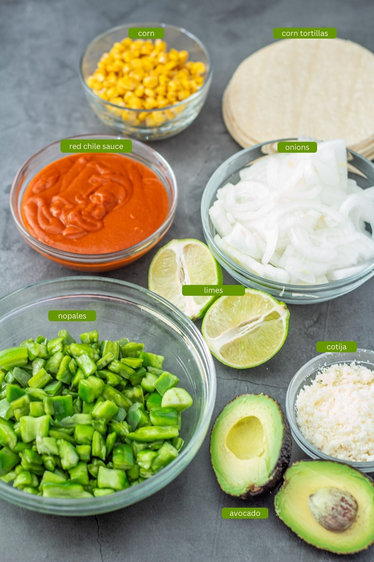 Tacos ingredients: Corn tortillas, onions, nopalitos, red chile sauce, corn, cilantro, lime, cotija, avocado.