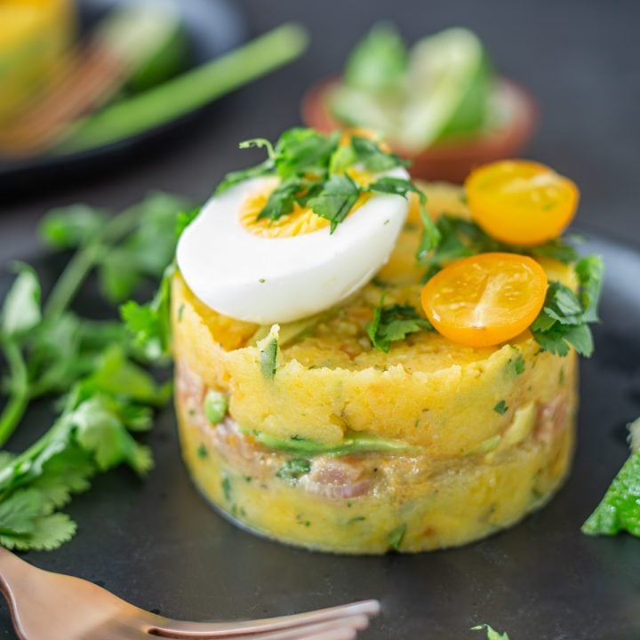 A close up of a single Peruvian cause on a black stoneware plate.