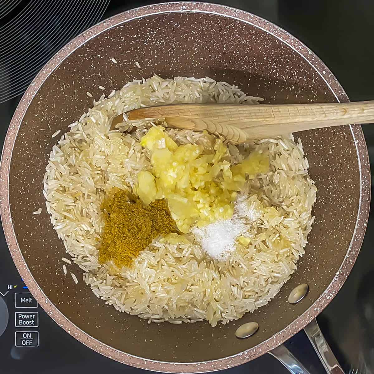 Ingredients for simple Peruvian rice - rice, cumin, garlic, salt - in a small saucepan.