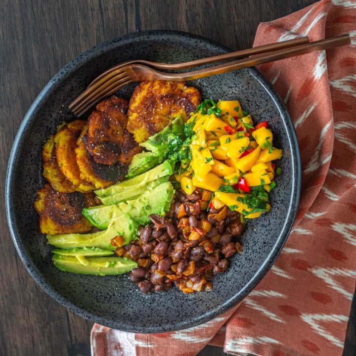 A black ceramic bowl with tropical buddha bowls components.