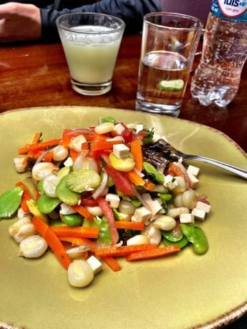 A ceramic plate with solterito and a pisco sour.