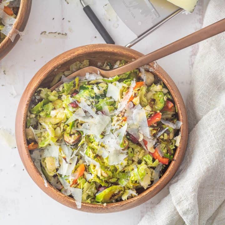 Roasted brussels sprouts salad in a wood bowl with copper fork.