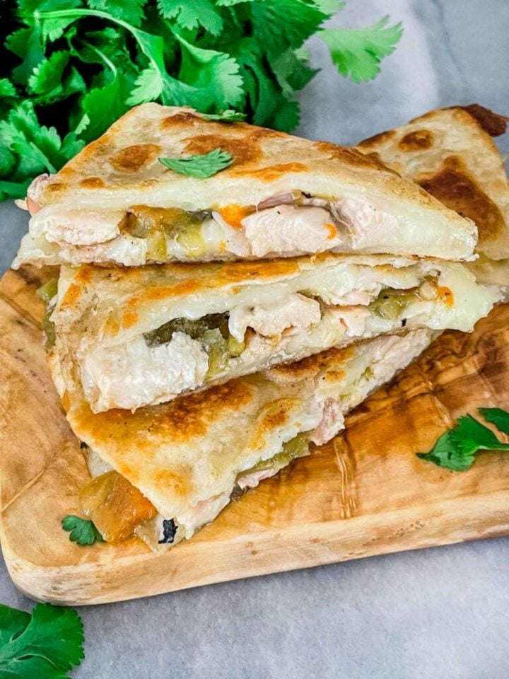 Chicken and Hatch green chile quesadillas on a wood cutting board.
