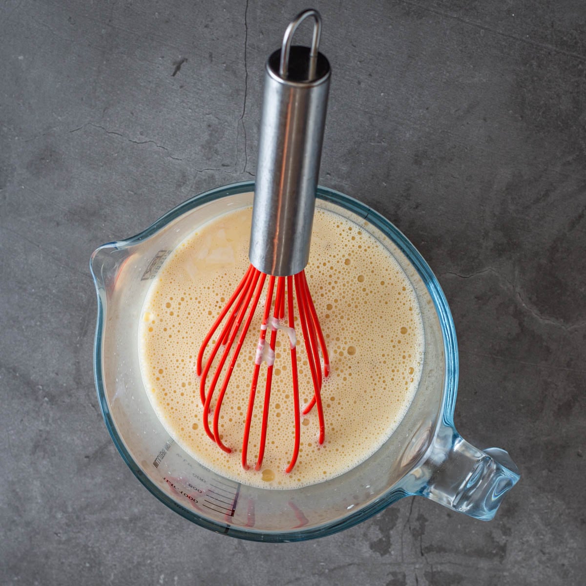 Step 2 - After egg yolks are whisked, they are tempered with ladles full of the hot cream mixture.