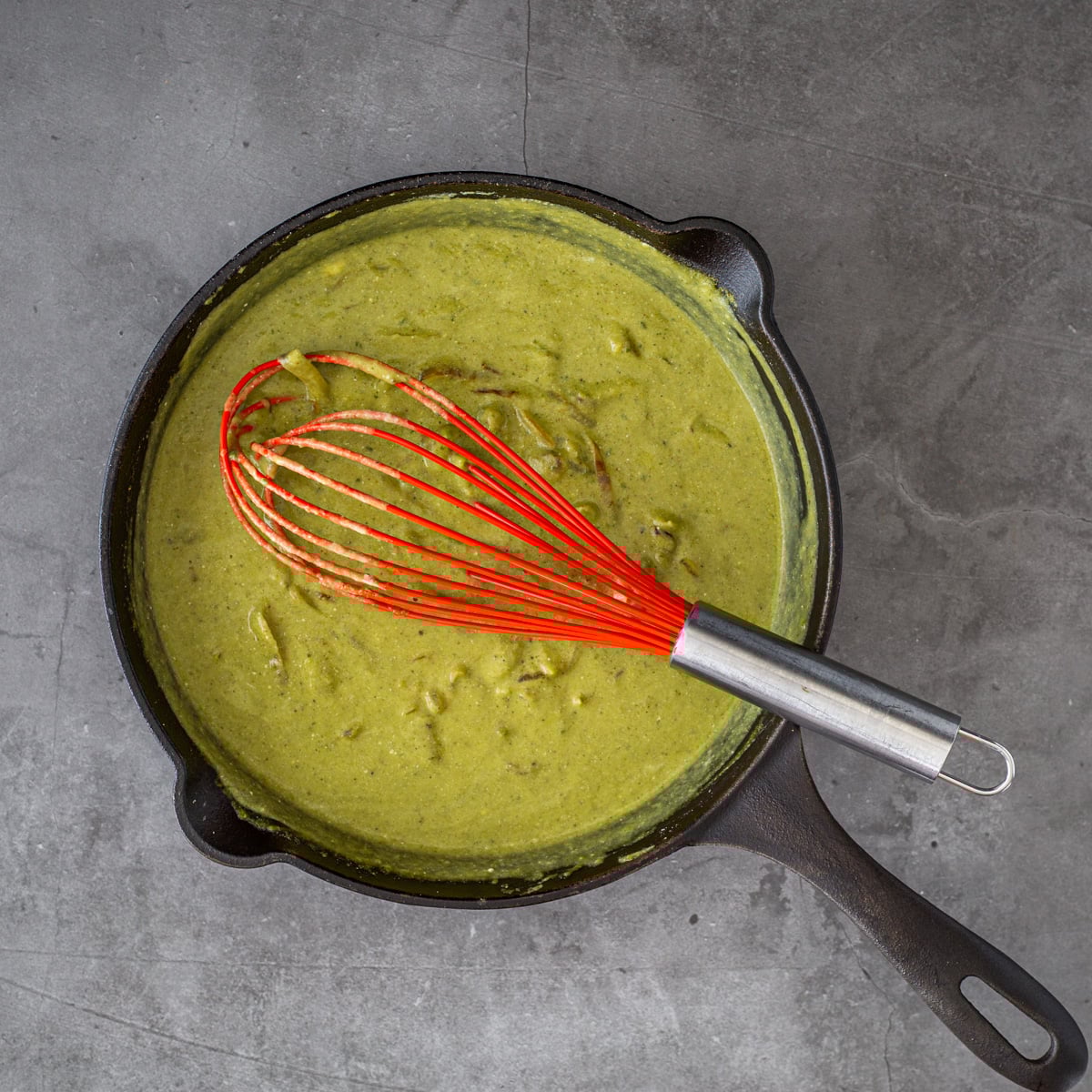 The creamy poblano sauce is whisked into the onion and masa mixture in a cast iron skillet.