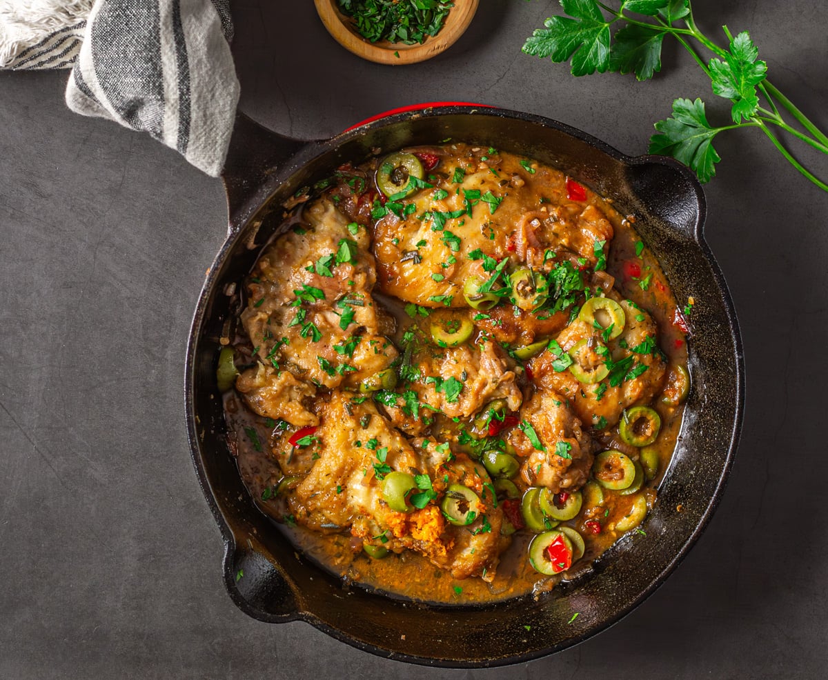 A close up of chicken with blood orange sauce in a cast iron skillet. 