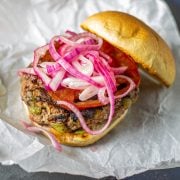 A single Mexican burger on a toasted KETO bun with avocado, pickled onion, and tomato.