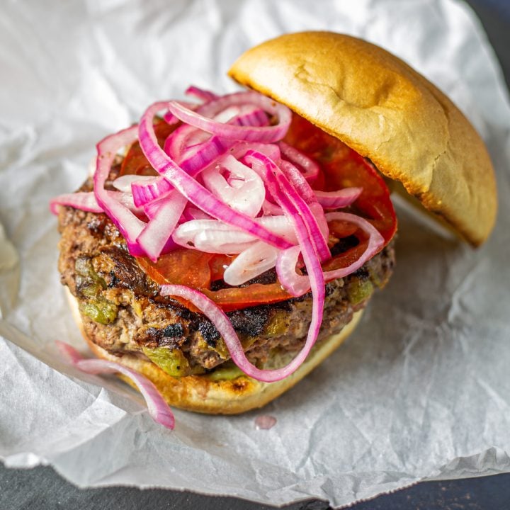 A single Mexican burger on a toasted KETO bun with avocado, pickled onion, and tomato.