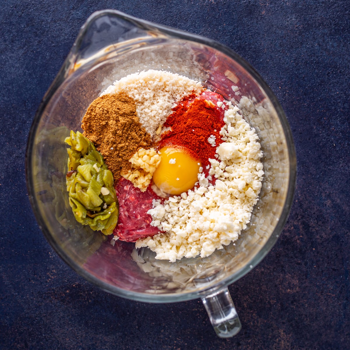 Step 1 - All ingredients for Mexican burger patties added to a mixing bowl before combining in a glass bowl.