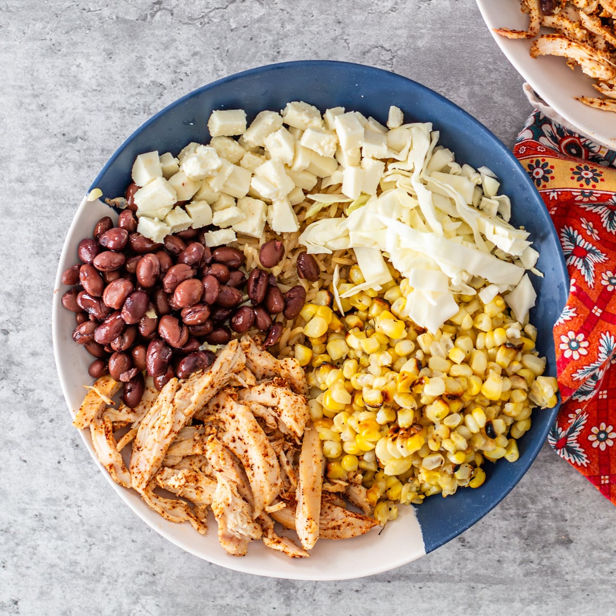 Step 1 - Arrange the chicken, corn, cabbage, cheese, and beans in a blue and white bowl.