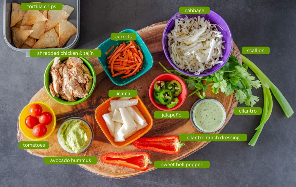 Ingredients for Mexican bento boxes including taj&iacute;n chicken, tortilla chips, cilantro ranch, and veggies.