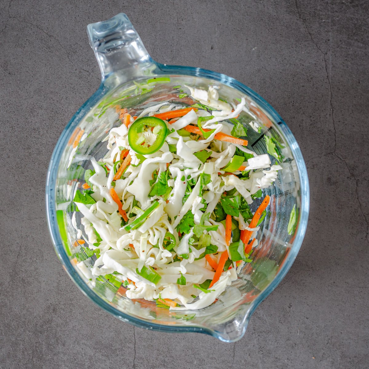 The veggie coleslaw is combined in a glass mixing bowl.