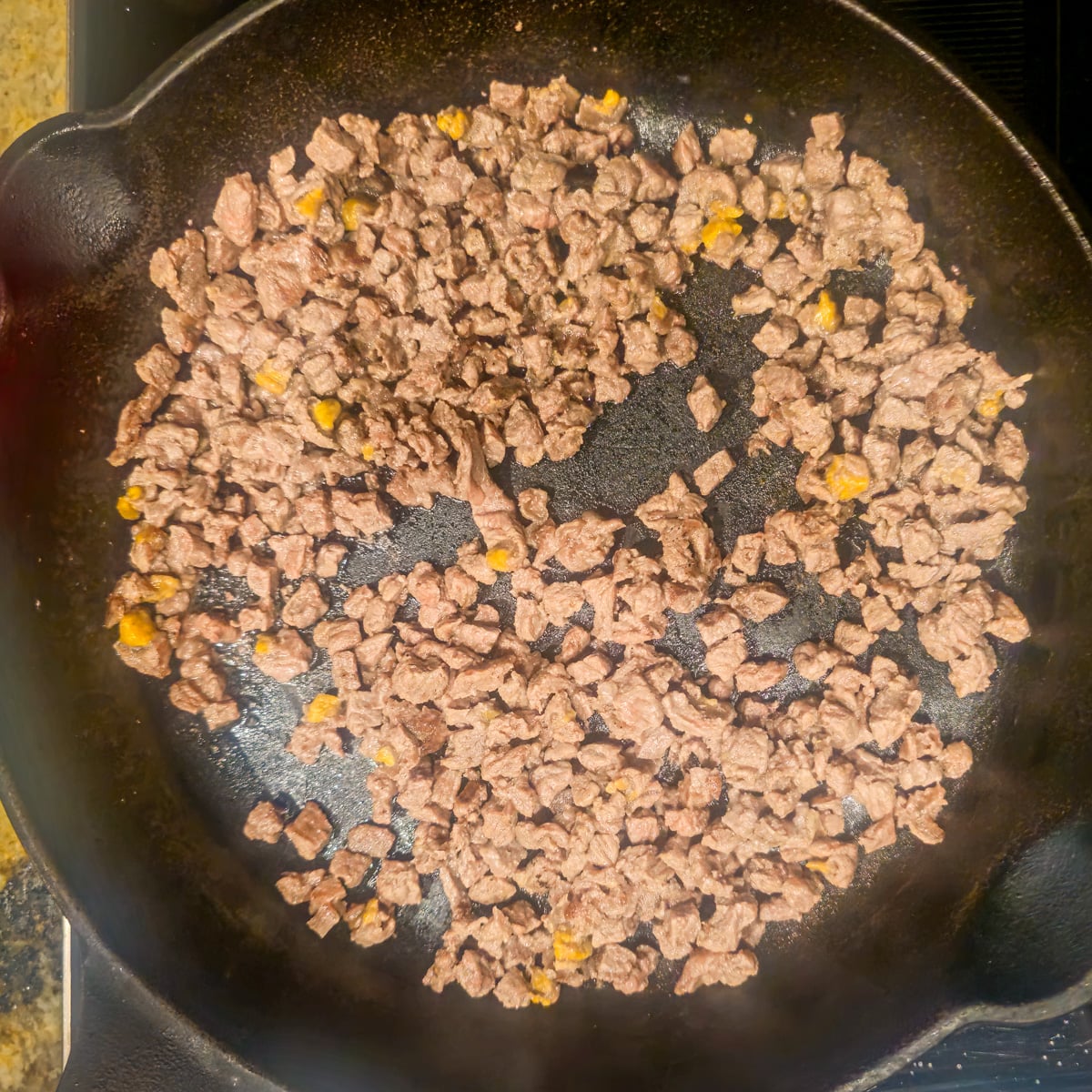 Step 1 - A cast iron skillet with minced bison being browned.