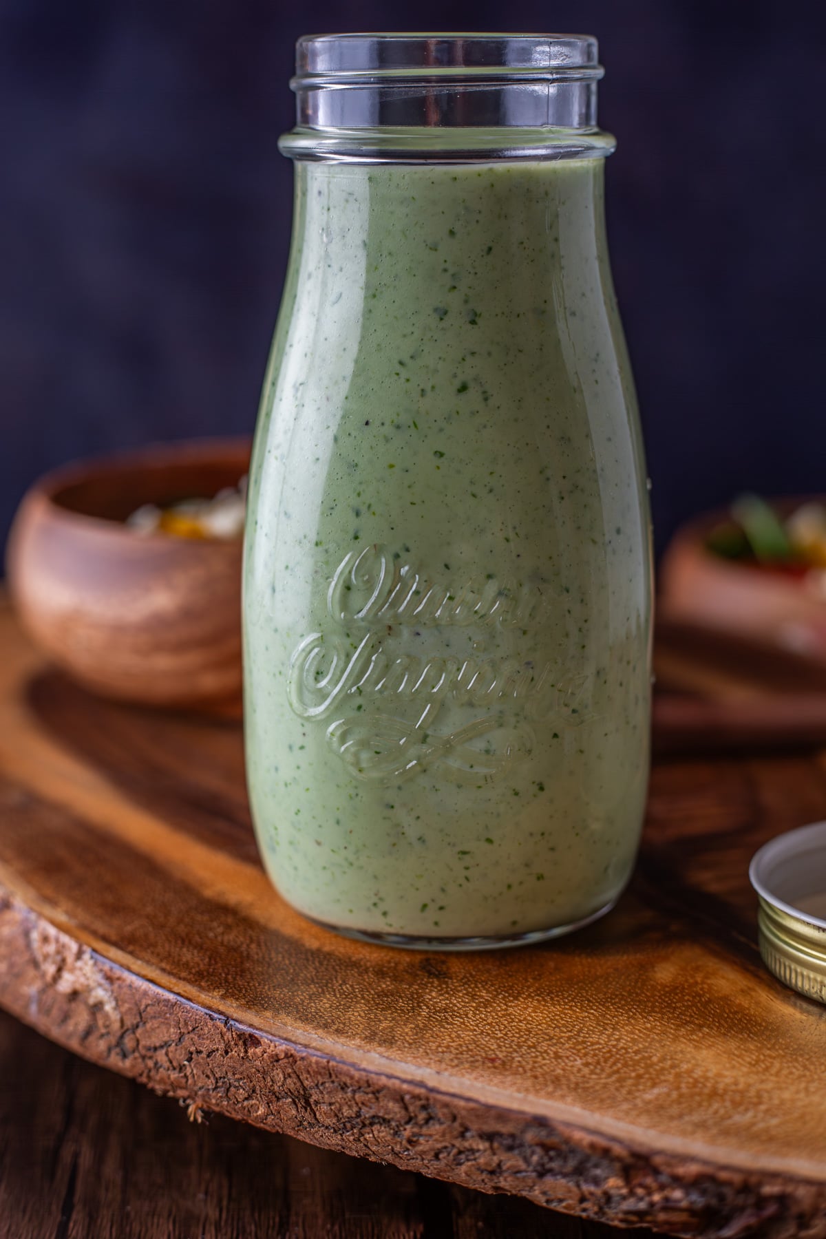 A close up of the cilantro lime ranch dressing on a wood cutting board.