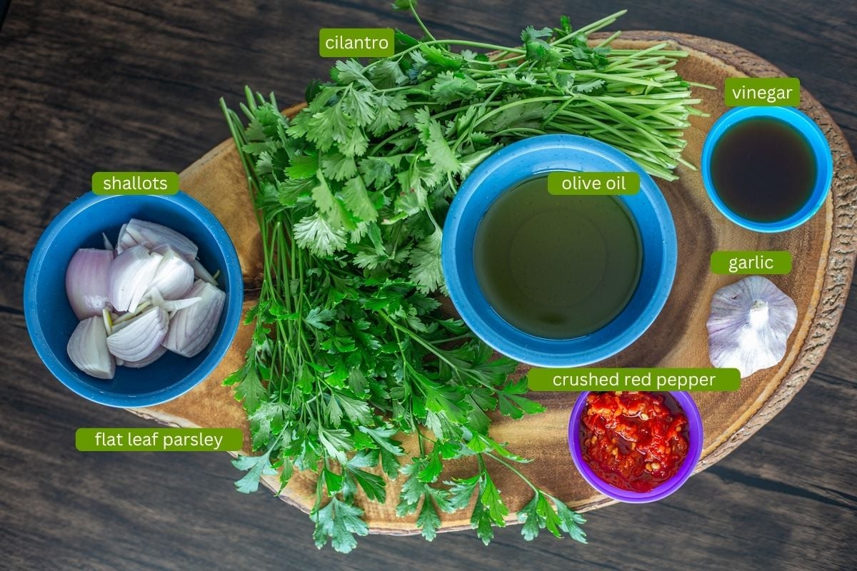 Chimichurri ingredients including oil, vinegar, parsley cilantro, Calabrian peppers, shallots, garlic.