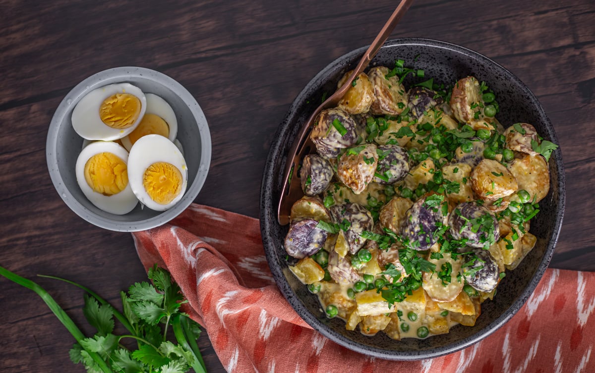 A closeup of the completed Peruvian potato salad with beets and hard boiled eggs and orange napkin.