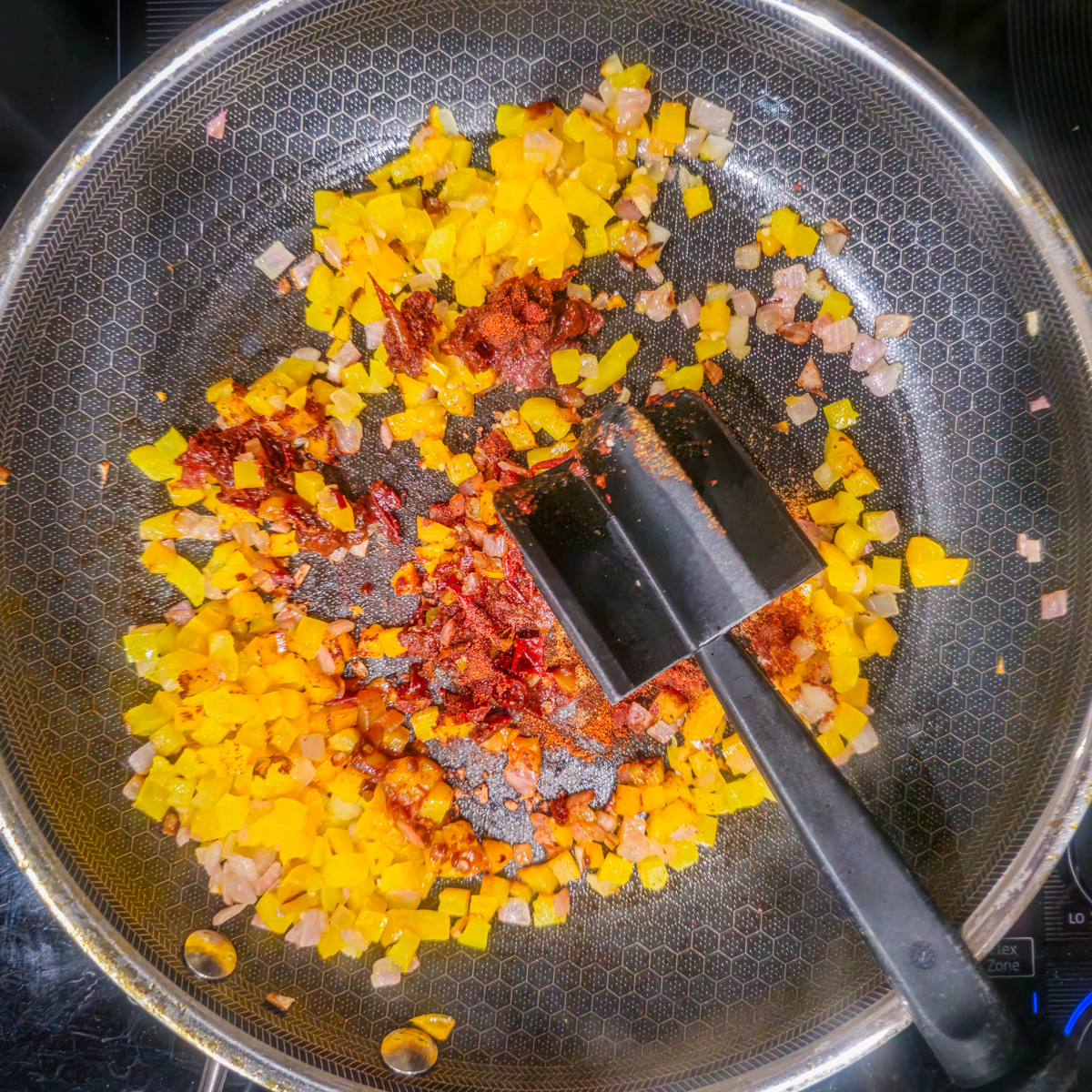 Bell pepper, onion, garlic, and spices are saut&eacute;ed in a stainless steel skillet.