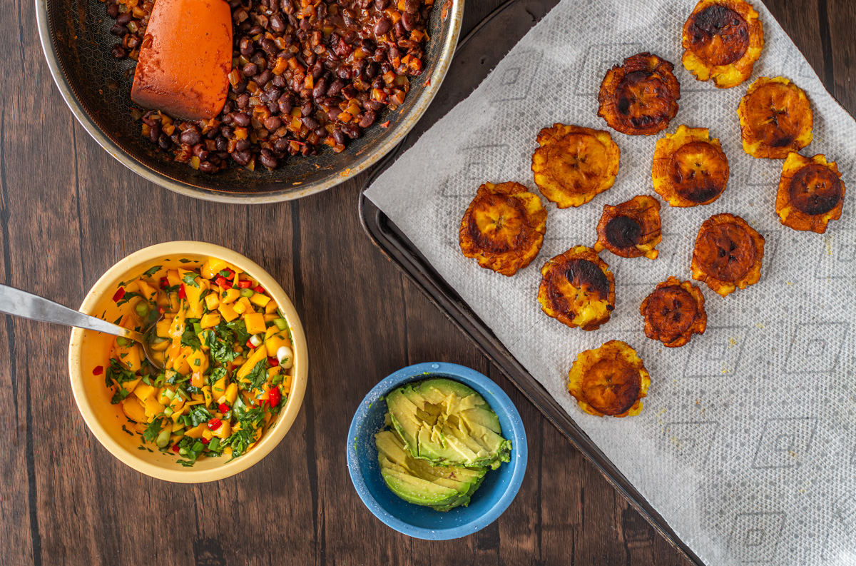 All the components of the tropical black bean buddha bowls are ready to assemble - black beans, mango salsa, avocadoes, and tostones.