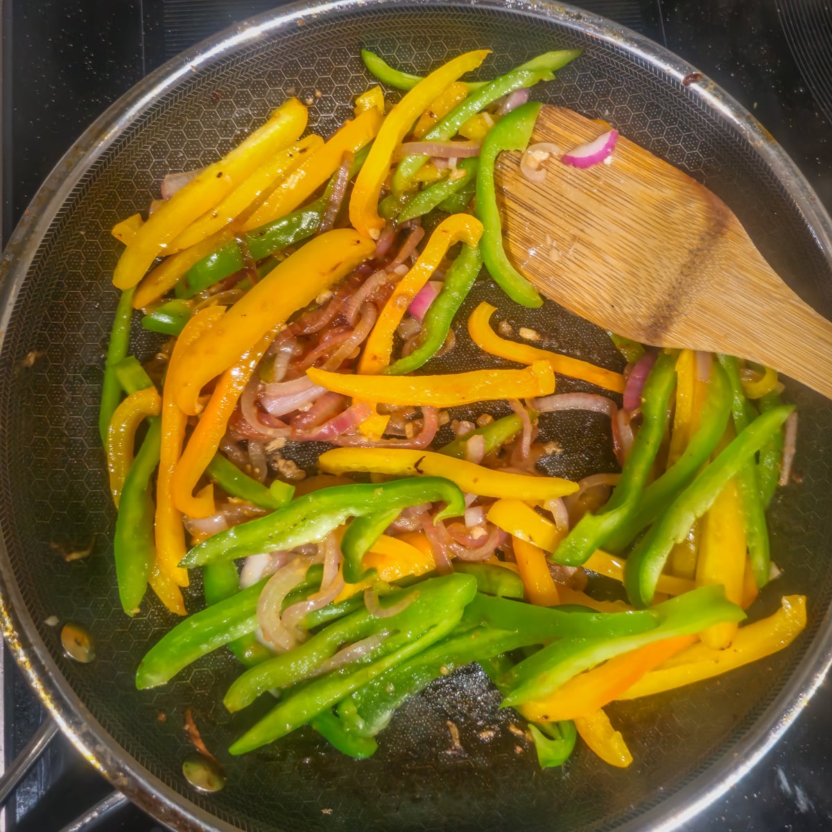 Step 3 - The bell pepper strips are added to the onion mixture in a saut&eacute; pan.