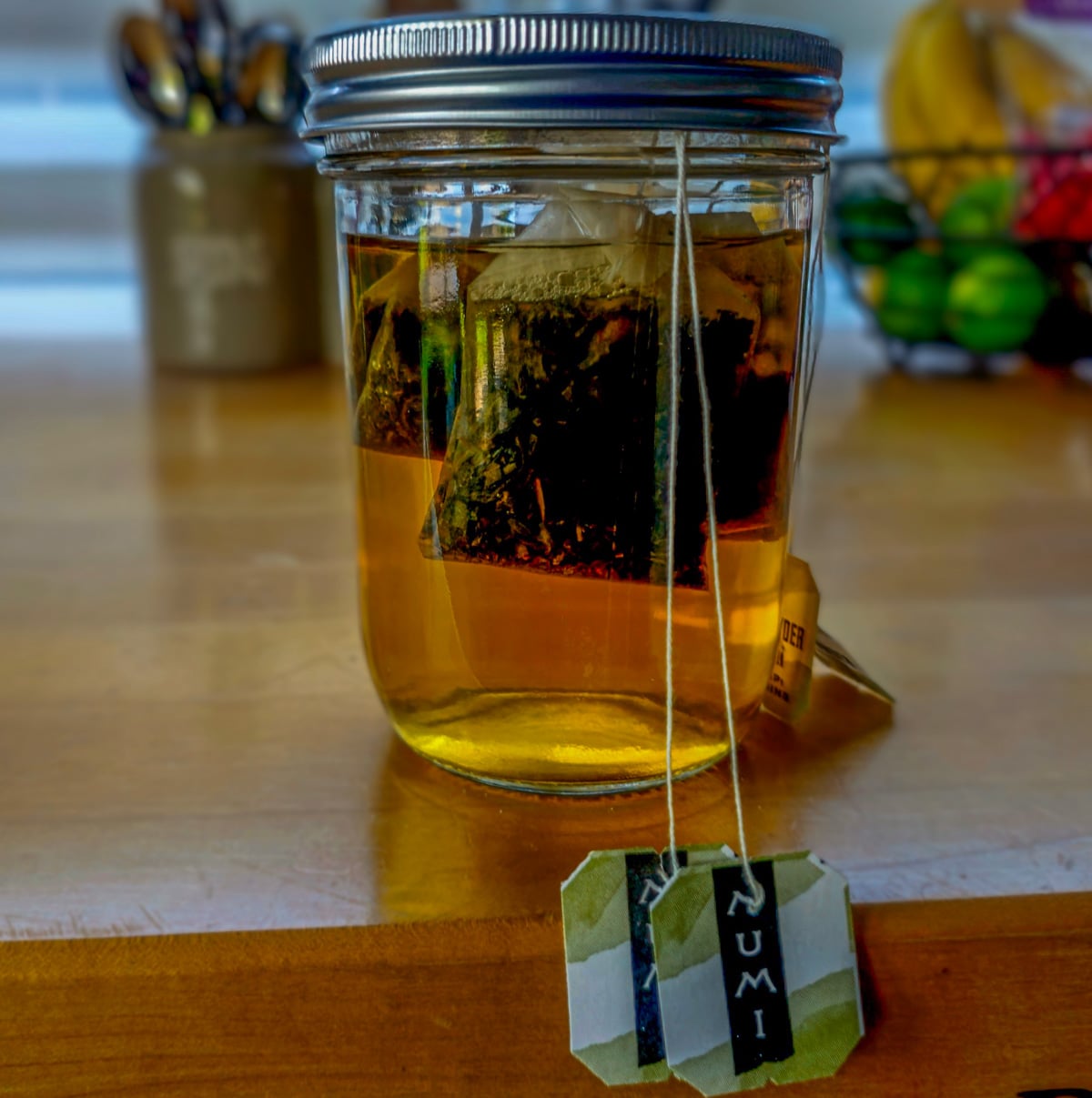 A glass mason jar with 4 green tea bags to make the strong green tea.
