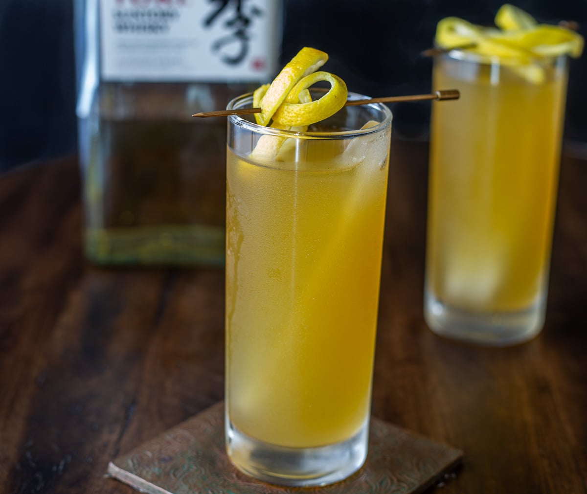 2 green tea cocktails with lemon garnish, and a bottle of Japanese whisky.