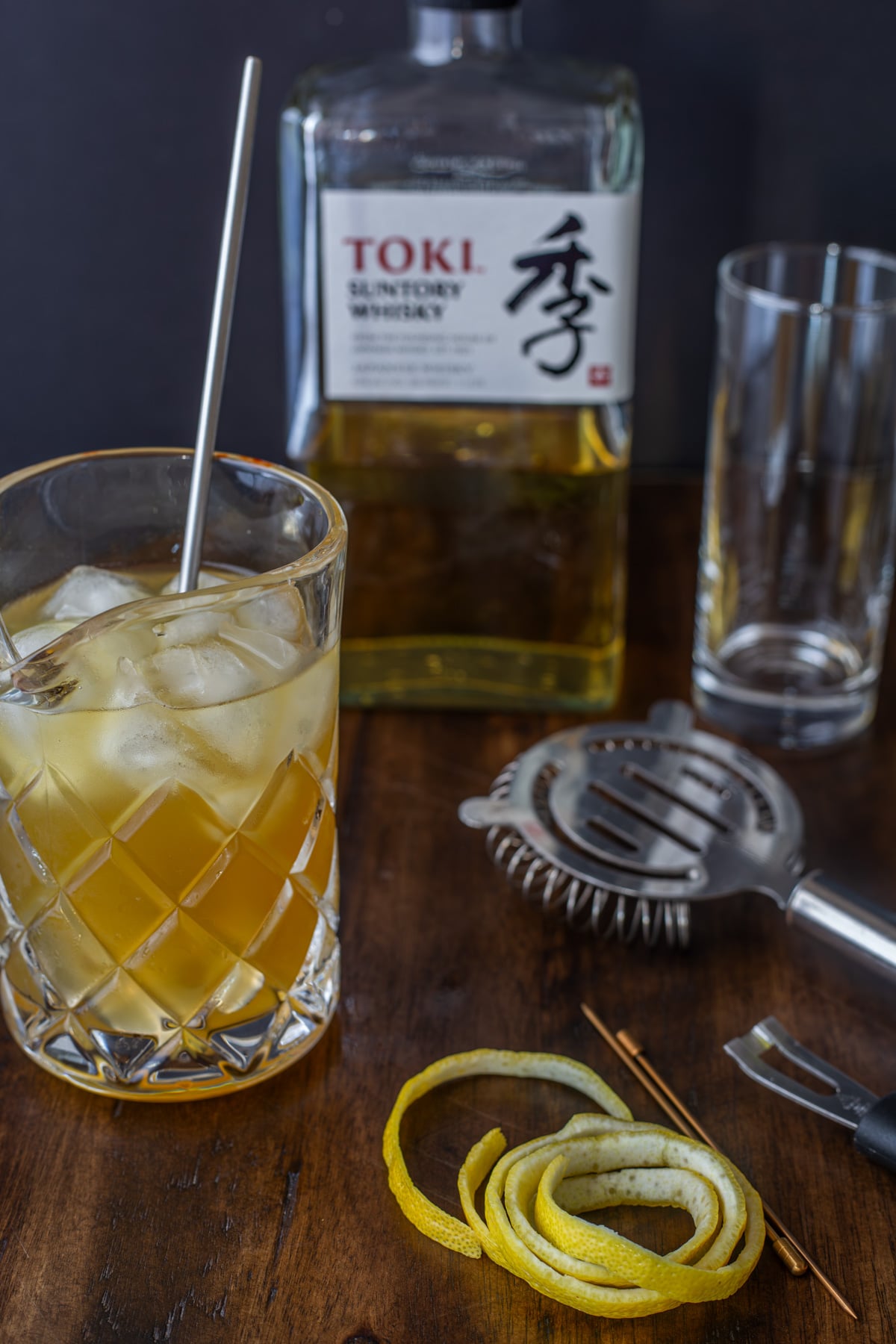 The process of making the whisky and green tea cocktail with a mixing glass, ingredients, ice, and spoon.