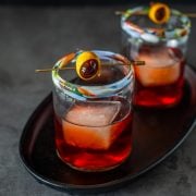 2 mezcal negroni cocktails on a cast iron oval tray.
