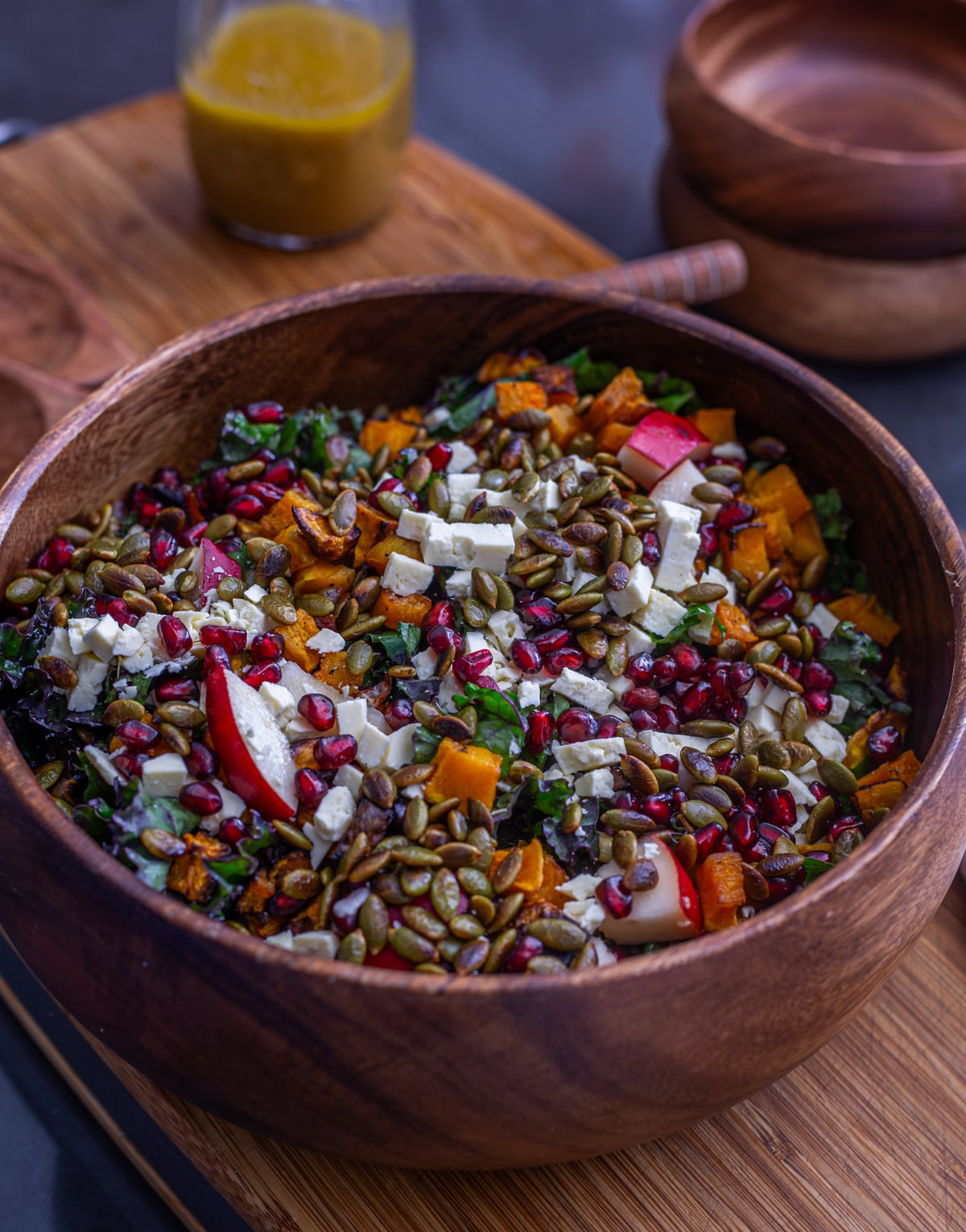 All of the fall kale salad ingredients in a wood salad bowl before it is dressed.