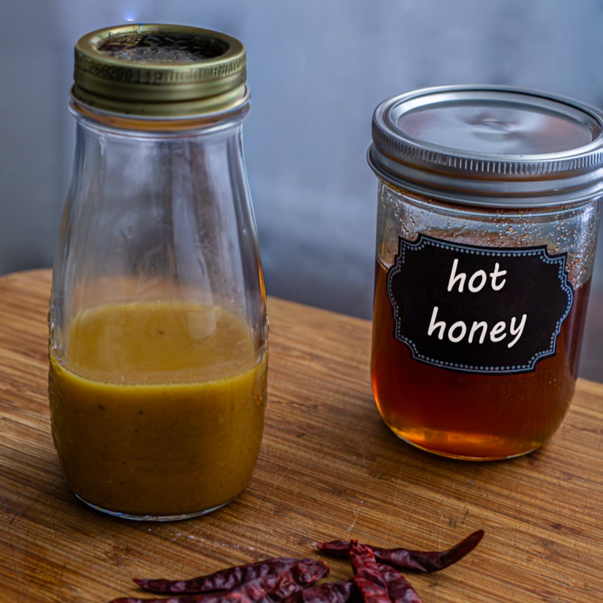 A jar of hot honey vinaigrette next to my homemade hot honey and chile de arbol.