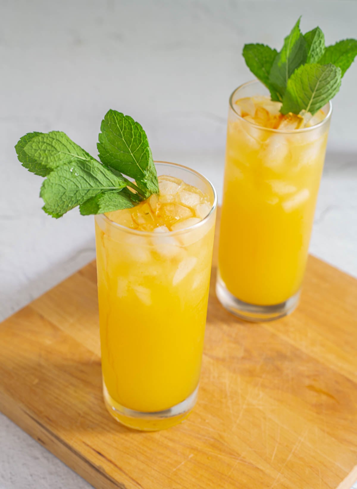 Chilcano de Maracuya in highball glasses with fresh mint sprigs on a green leaf tray with ice cubes.