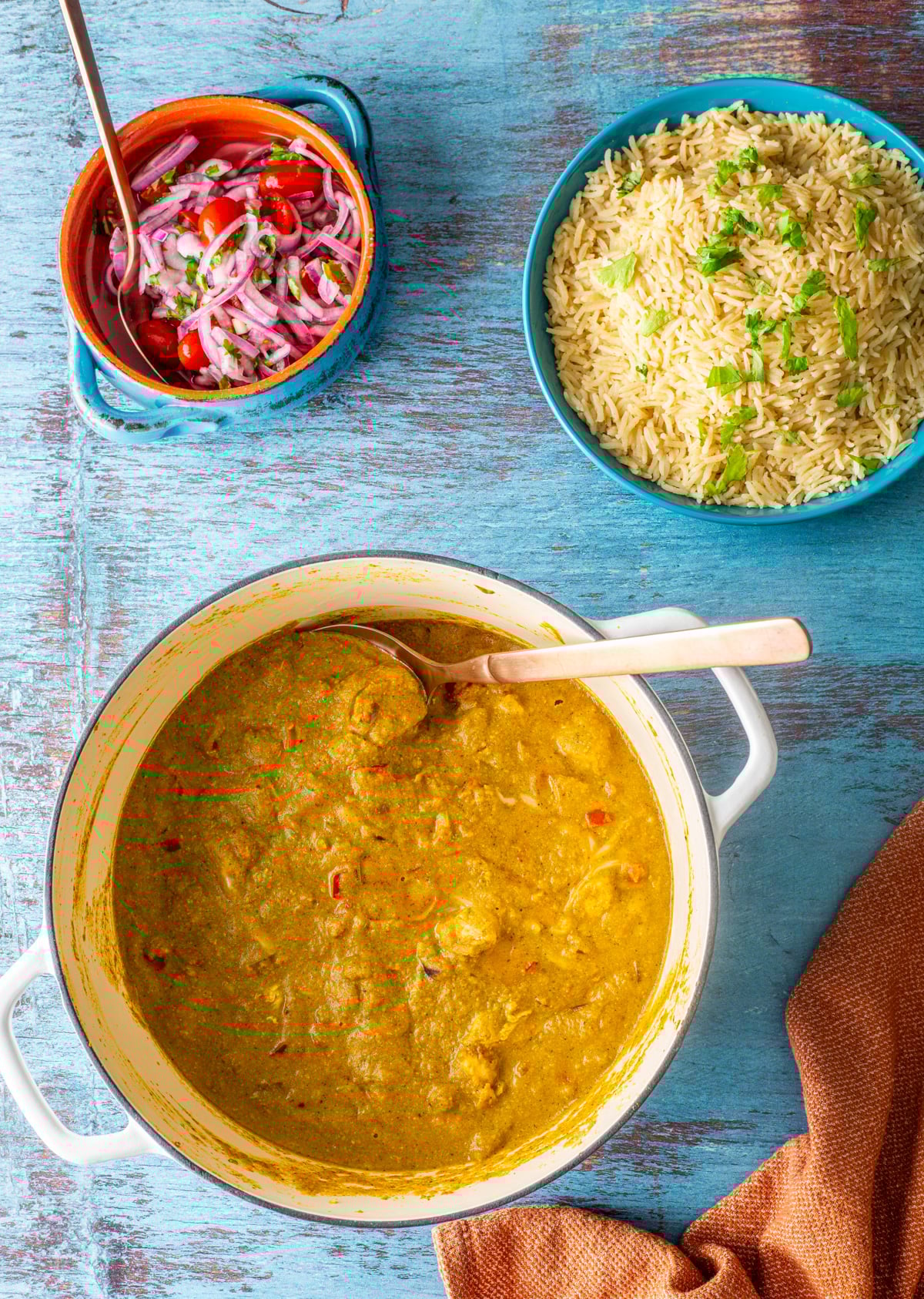 A white dutch oven with the completed pep&iacute;an de choclo stew, a bowl of Peruvian rice, and salsa criolla.