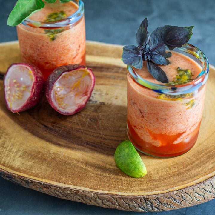 Glasses of agua fresca, 2 squeezed lime halves, 2 passionfruit halves with pulp removed.