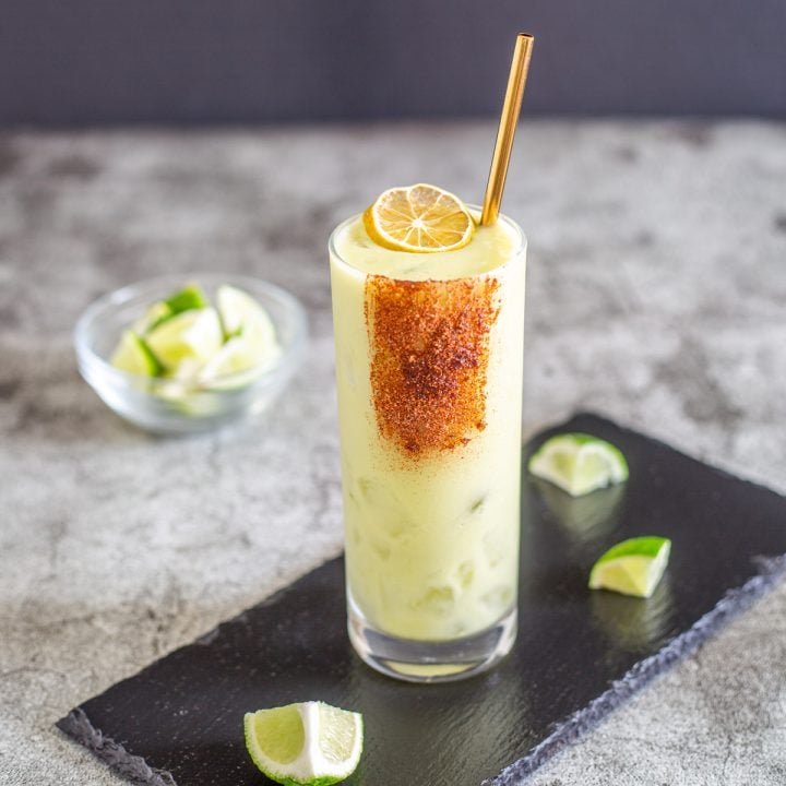 A single coconut avocado margarita with mezcal garnished with a dried lime slice.