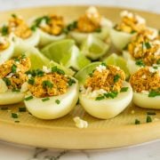 A close up of a yellow plate with Mexican deviled eggs with no mayo.