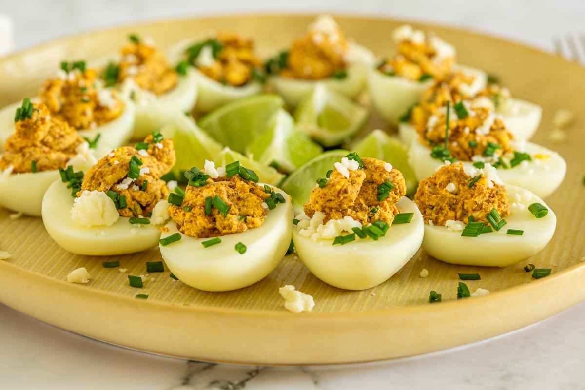 A close up of a yellow plate with Mexican deviled eggs with no mayo.