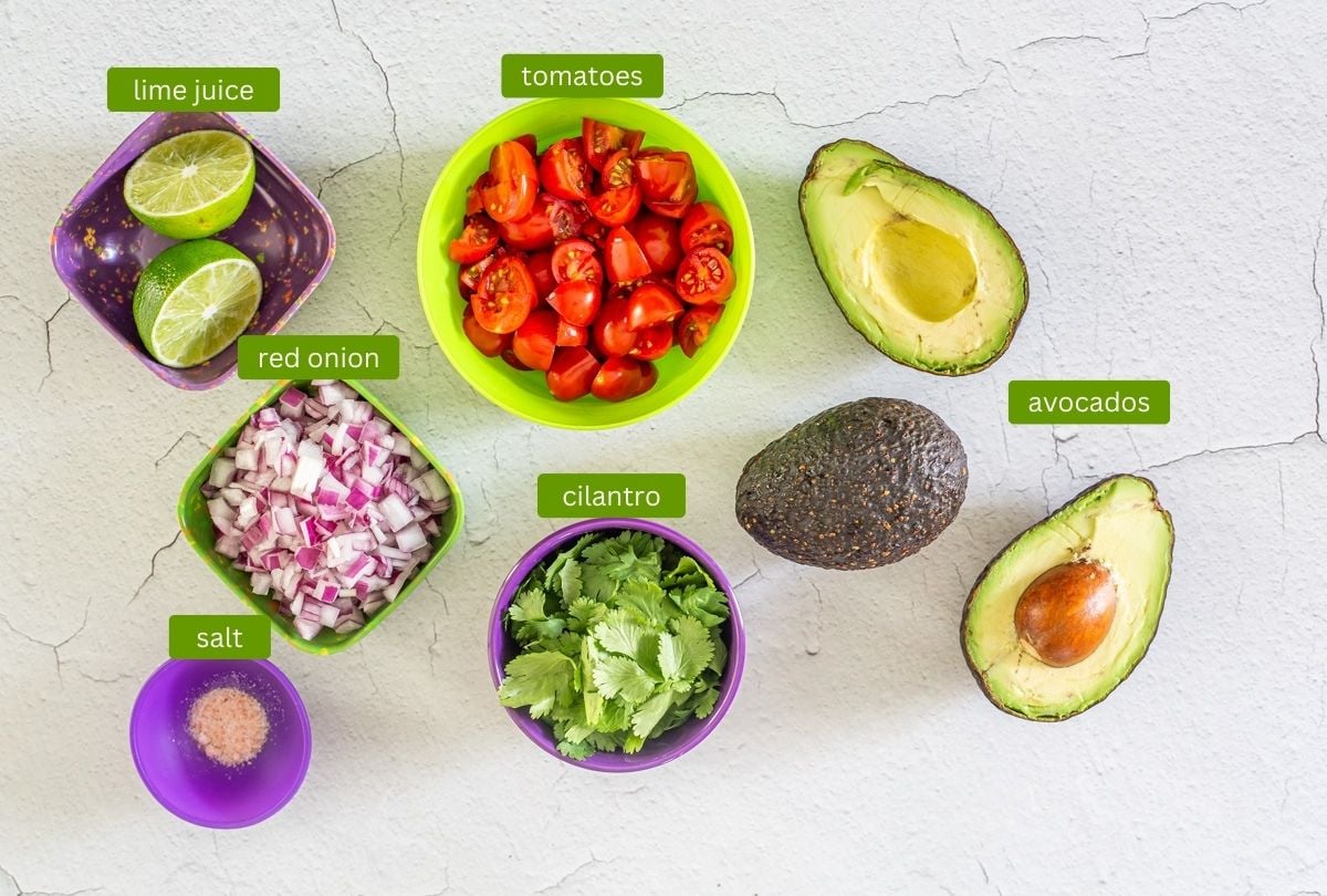 Peruvian eggs benedict guacamole ingredients including avocado, tomatoes, and red onion.